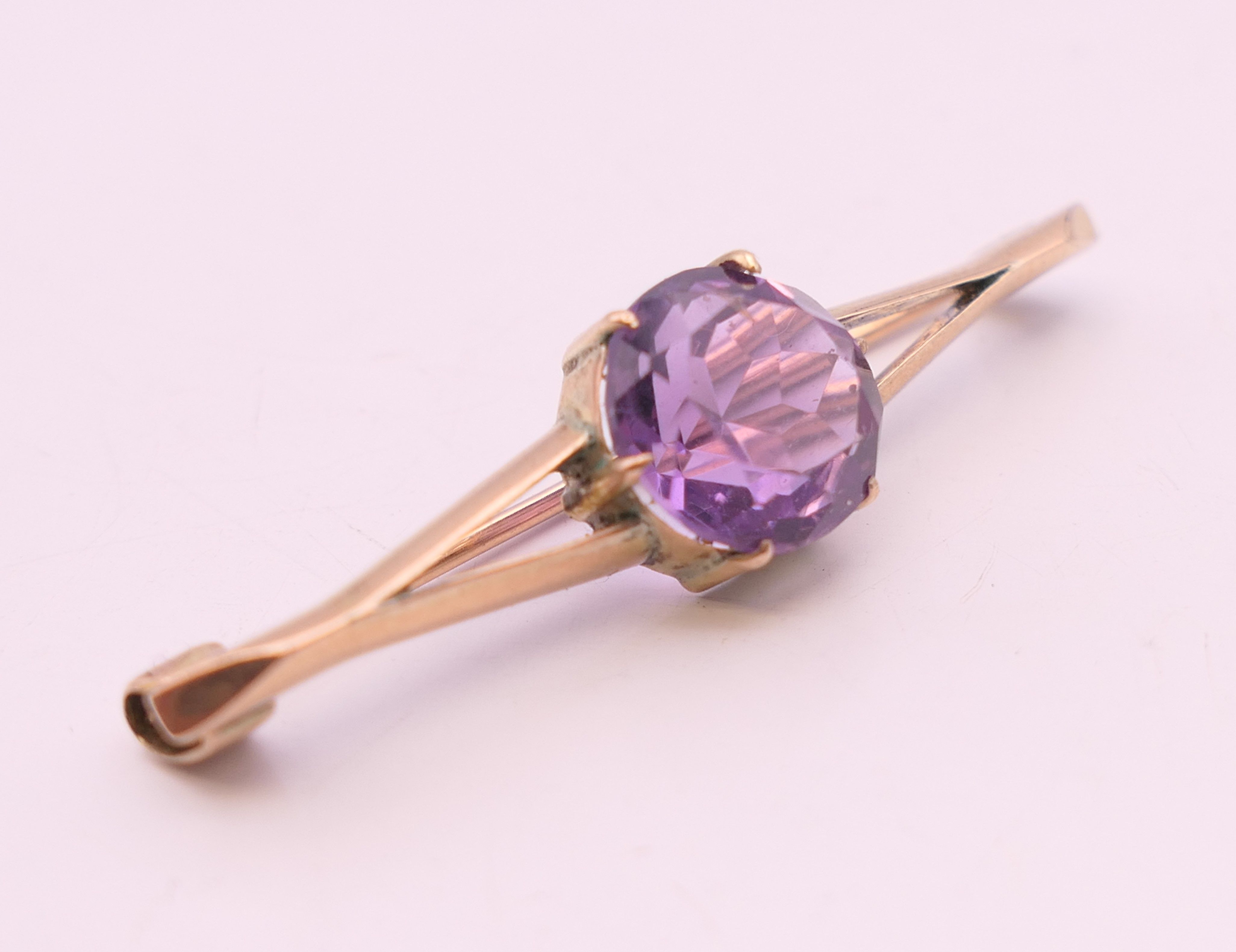 An unmarked 9 ct gold and amethyst bar brooch. 4 cm wide. 2.9 grammes total weight. - Image 2 of 3