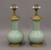 A pair of Chinese ormolu mounted green celadon glazed table lamps, both incised with flowers, etc.