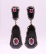 A pair of black onyx, diamond and ruby earrings. 5 cm high.