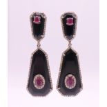 A pair of black onyx, diamond and ruby earrings. 5 cm high.