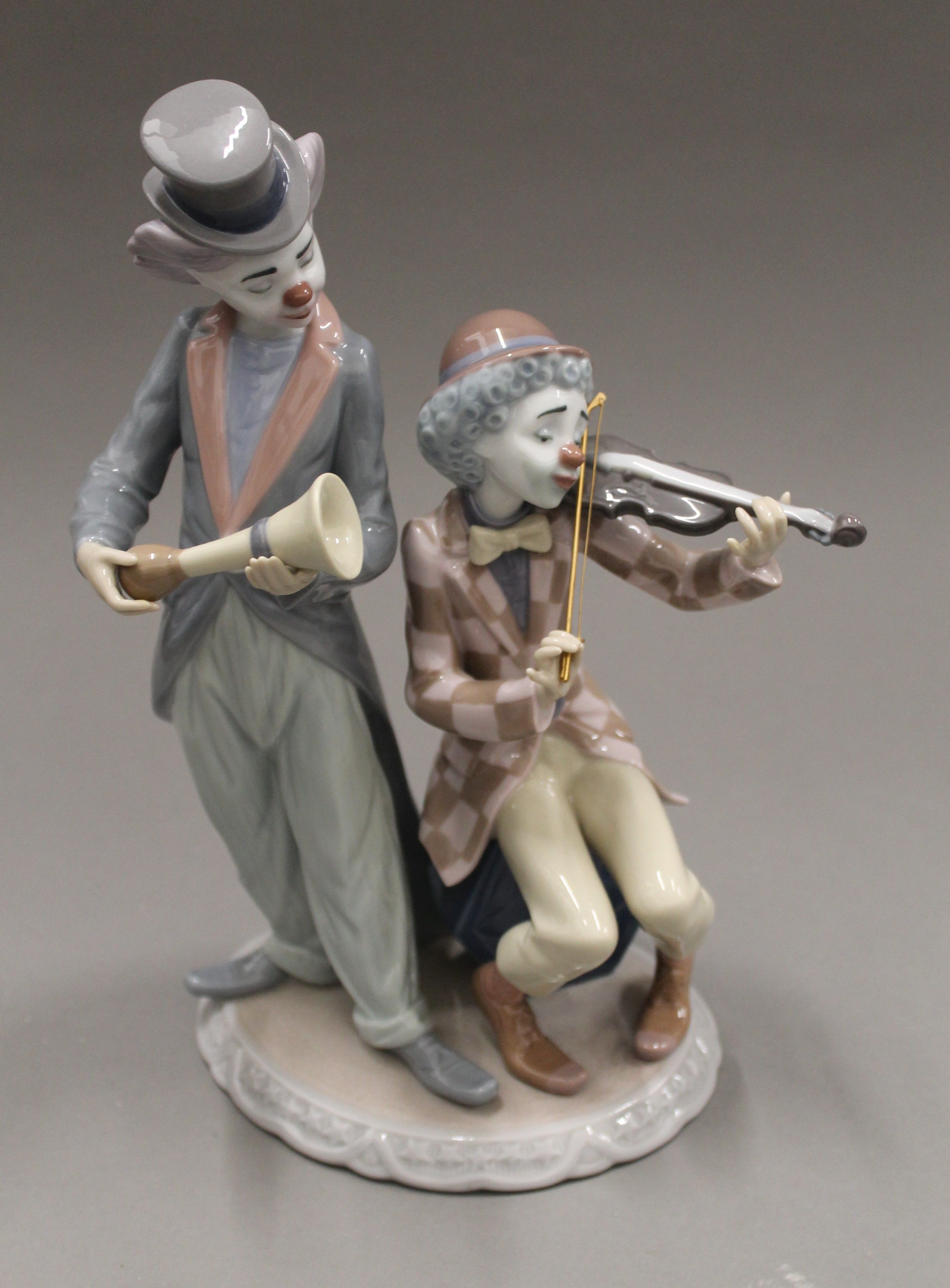 A Lladro clown musician group. 25 cm high.