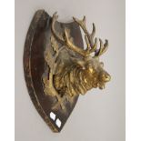 A gilt metal stags head, mounted on a shield. 33 cm high.