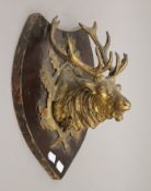 A gilt metal stags head, mounted on a shield. 33 cm high.