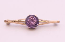 An unmarked 9 ct gold and amethyst bar brooch. 4 cm wide. 2.9 grammes total weight.