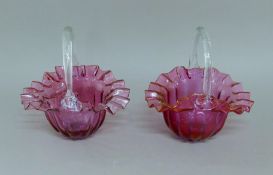 Two cranberry glass baskets. The largest 23 cm long.