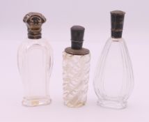 Three silver topped scent bottles. The largest 10.5 cm high.