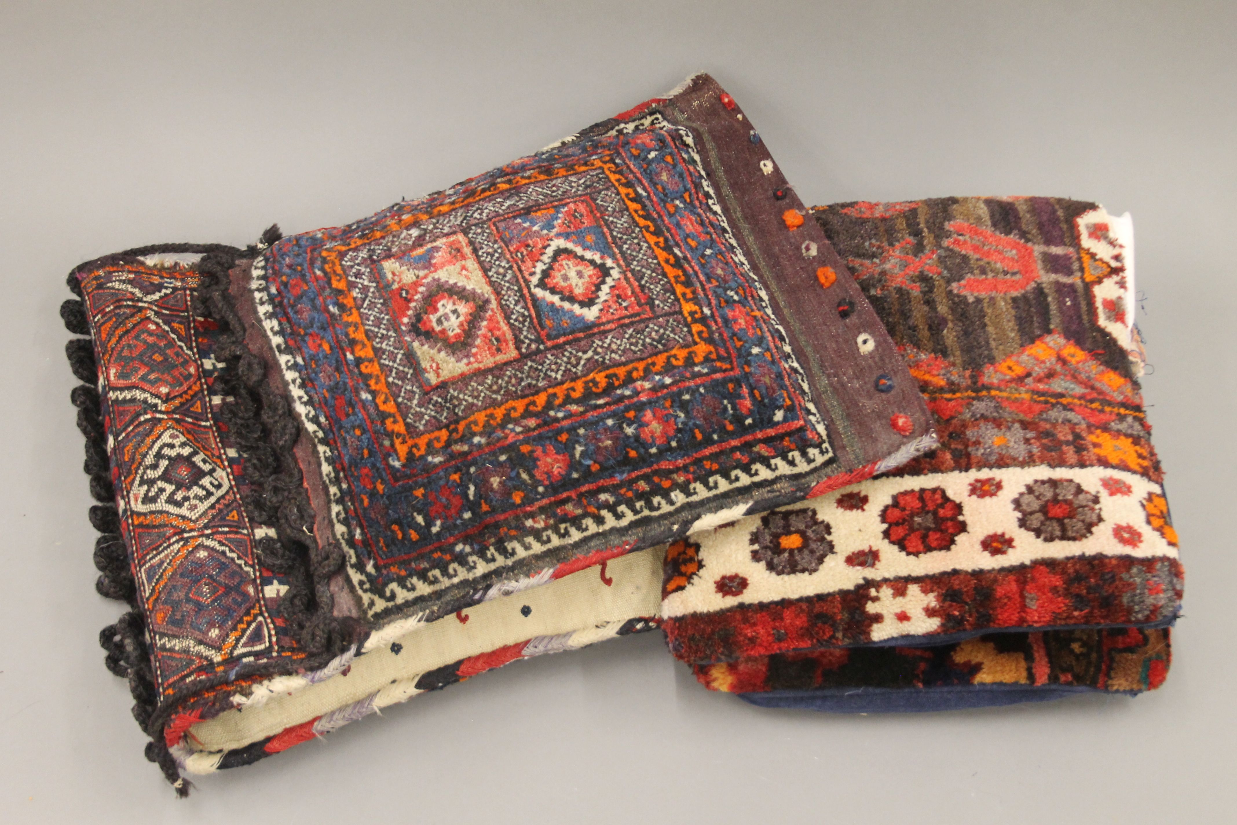 A Persian saddle bag rug and two cushions. The former approximately 98 cm long.