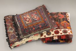 A Persian saddle bag rug and two cushions. The former approximately 98 cm long.
