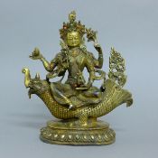 A gilt bronze model of a multi-armed deity riding a mythical beast. 26 cm high.