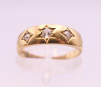 An 18 ct gold three stone gypsy set diamond ring. Ring size K. 3 grammes total weight.