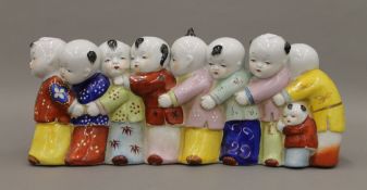 A Chinese porcelain model of nine boys. 35 cm long.