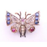 An unmarked gold and silver diamond, sapphire, ruby and pearl set brooch formed as a butterfly.