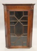 A George III line inlaid mahogany glazed hanging corner cabinet. 71.5 cm wide.