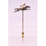 An unmarked diamond and ruby set horse and jockey stick pin. 2.5 cm wide. 2.4 grammes total weight.