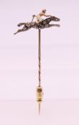 An unmarked diamond and ruby set horse and jockey stick pin. 2.5 cm wide. 2.4 grammes total weight.
