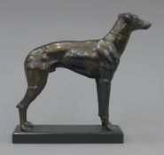 An antique spelter greyhound standing figure on a matching colour metal base. 18 cm high.