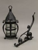 An Arts and Crafts style blackened metal planished storm lantern with scrolled bracket.