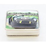 A silver pill box depicting a racing car. 3.25 x 2.5 cm.