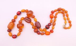 A Victorian Baltic amber necklace with engraved beads and gold clasp. 75 cm long. 64.