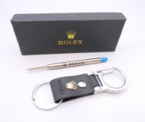 A key ring stamped Rolex, boxed and a Rolex pen refill. Key ring 10 cm long.