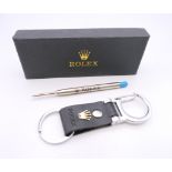 A key ring stamped Rolex, boxed and a Rolex pen refill. Key ring 10 cm long.