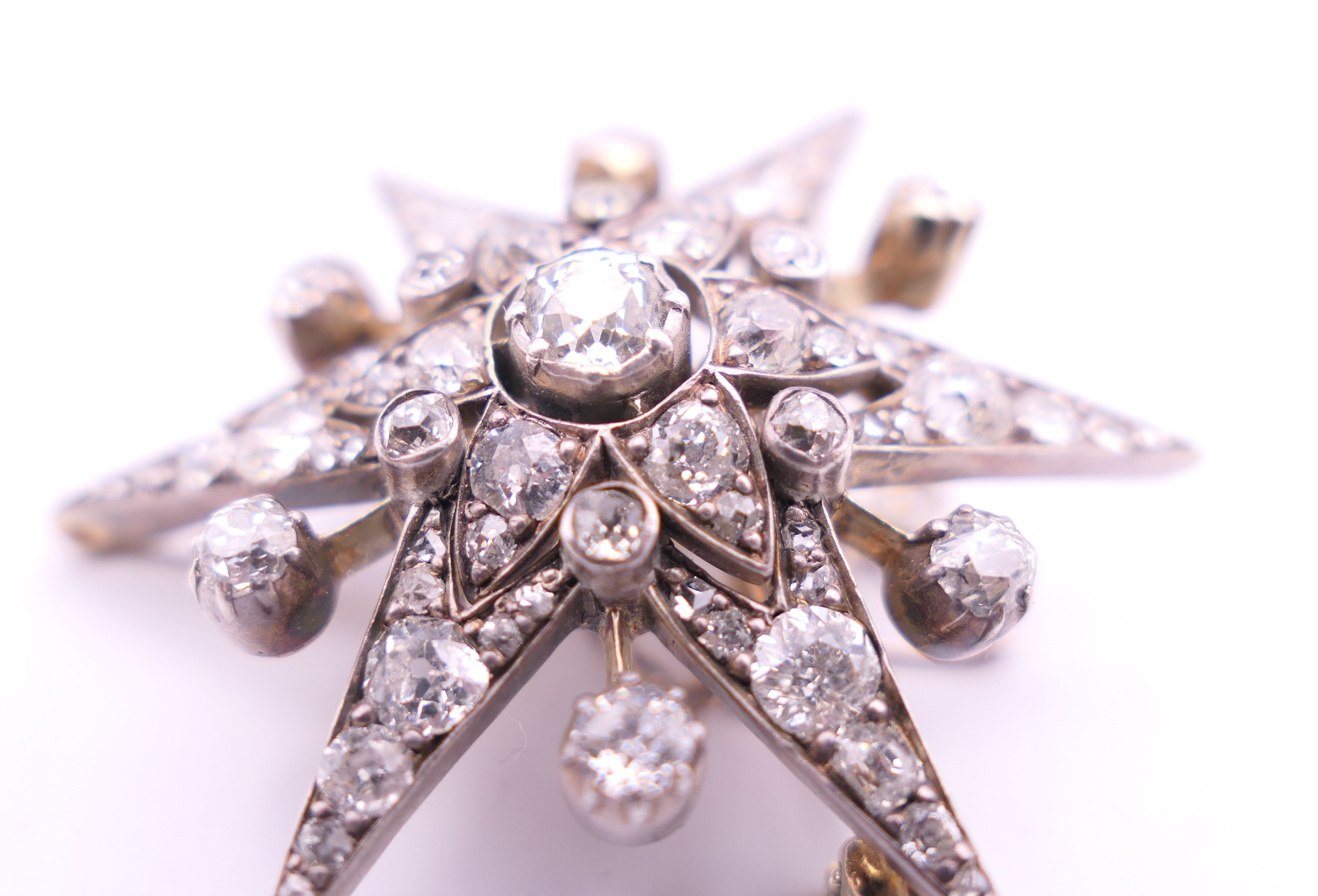 An unmarked gold diamond set star form pendant/brooch. 4 cm high. 10.7 grammes total weight. - Image 5 of 6