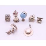 A collection of silver charms including a globe, typewriter, umbrella, hat, etc.