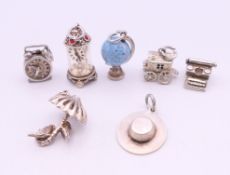 A collection of silver charms including a globe, typewriter, umbrella, hat, etc.