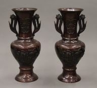 A pair of Japanese patinated bronze vases with repousse decoration. 24 cm high.