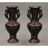 A pair of Japanese patinated bronze vases with repousse decoration. 24 cm high.