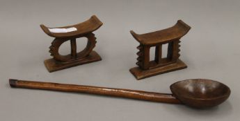 A finely carved South African wooden ladle and two small wooden headrests. The former 44 cm long.