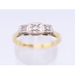 An 18 ct gold and platinum three stone diamond ring. Ring size O/P. 2.6 grammes total weight.