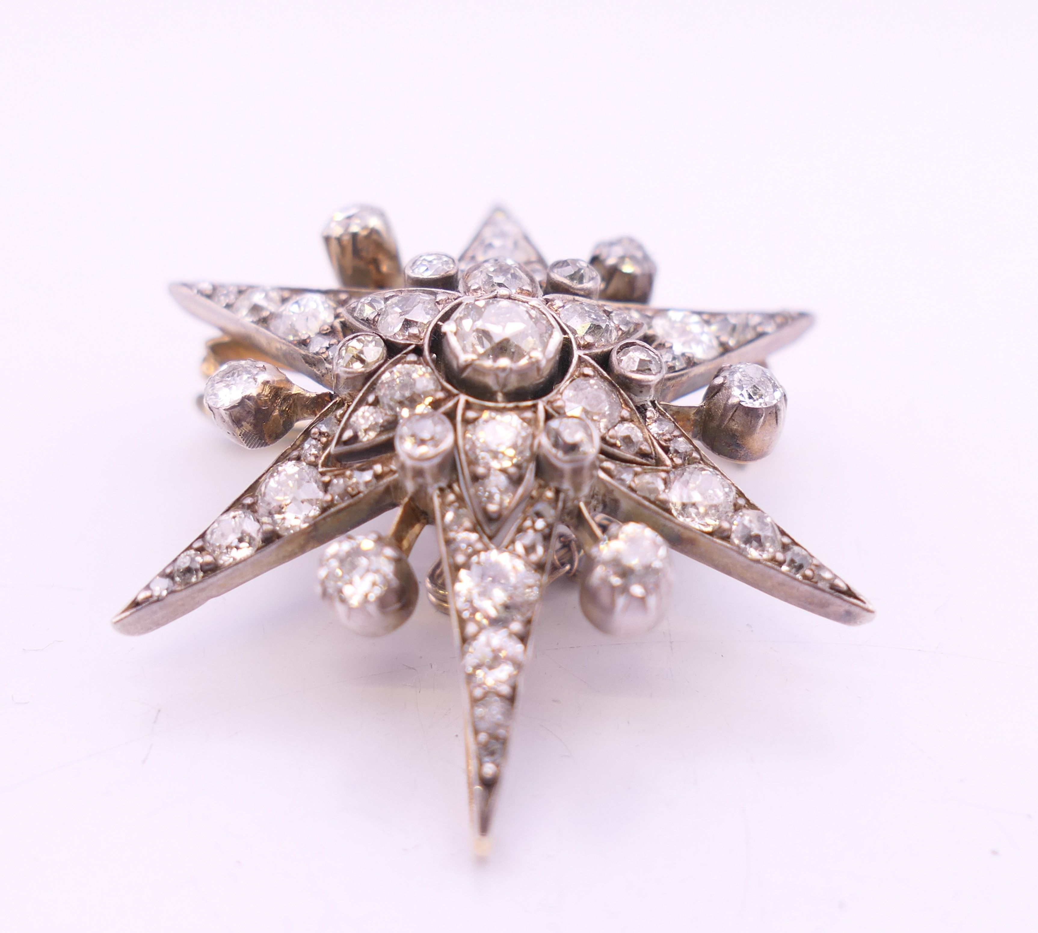 An unmarked gold diamond set star form pendant/brooch. 4 cm high. 10.7 grammes total weight. - Image 2 of 6