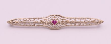 A 10 K white gold and ruby pierced bar brooch. 6 cm long. 2.6 grammes total weight.