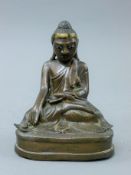 An 18th century bronze model of Buddha with glass inset eyes. 16 cm high.