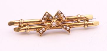 A 15 ct gold bar brooch decorated with a seed pearl bow. 4.5 cm long. 4.3 grammes total weight.