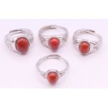 Four silver and coral adjustable rings.