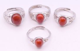 Four silver and coral adjustable rings.