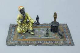 A cold painted bronze model of an Arab antiquity dealer. 18.5 cm long.