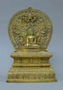 A bronze model of Buddha seated before a shrine. 28 cm high.