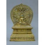 A bronze model of Buddha seated before a shrine. 28 cm high.