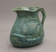 An Arts and Crafts green jug decorated with a galleon. 20 cm high.