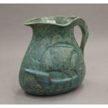 An Arts and Crafts green jug decorated with a galleon. 20 cm high.