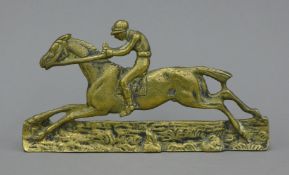 A brass mantle ornament formed as a racehorse with jockey up. 17 cm long.