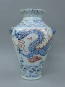 A porcelain vase decorated with a dragon, twin lion mask handles and Arabic script.