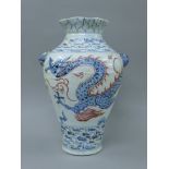 A porcelain vase decorated with a dragon, twin lion mask handles and Arabic script.