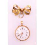 An 18 k gold cased fob watch with gold plated bow. Watch 2.5 cm diameter, bow 3 cm long.