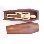 A miniature coffin enclosing a bone skeleton. Coffin 12 cm long.