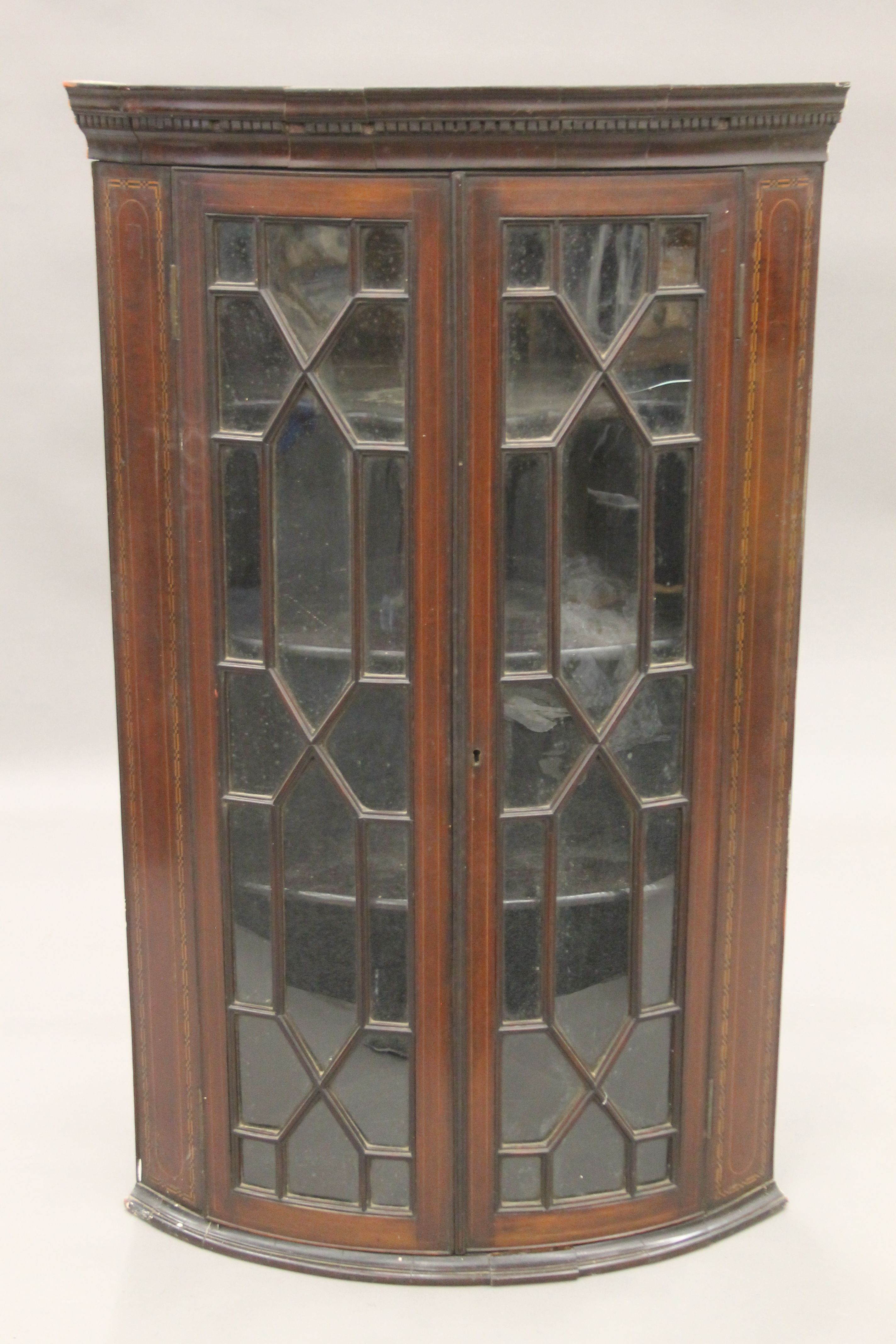 A George III inlaid mahogany glazed hanging corner cabinet. 69 cm wide.