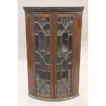 A George III inlaid mahogany glazed hanging corner cabinet. 69 cm wide.